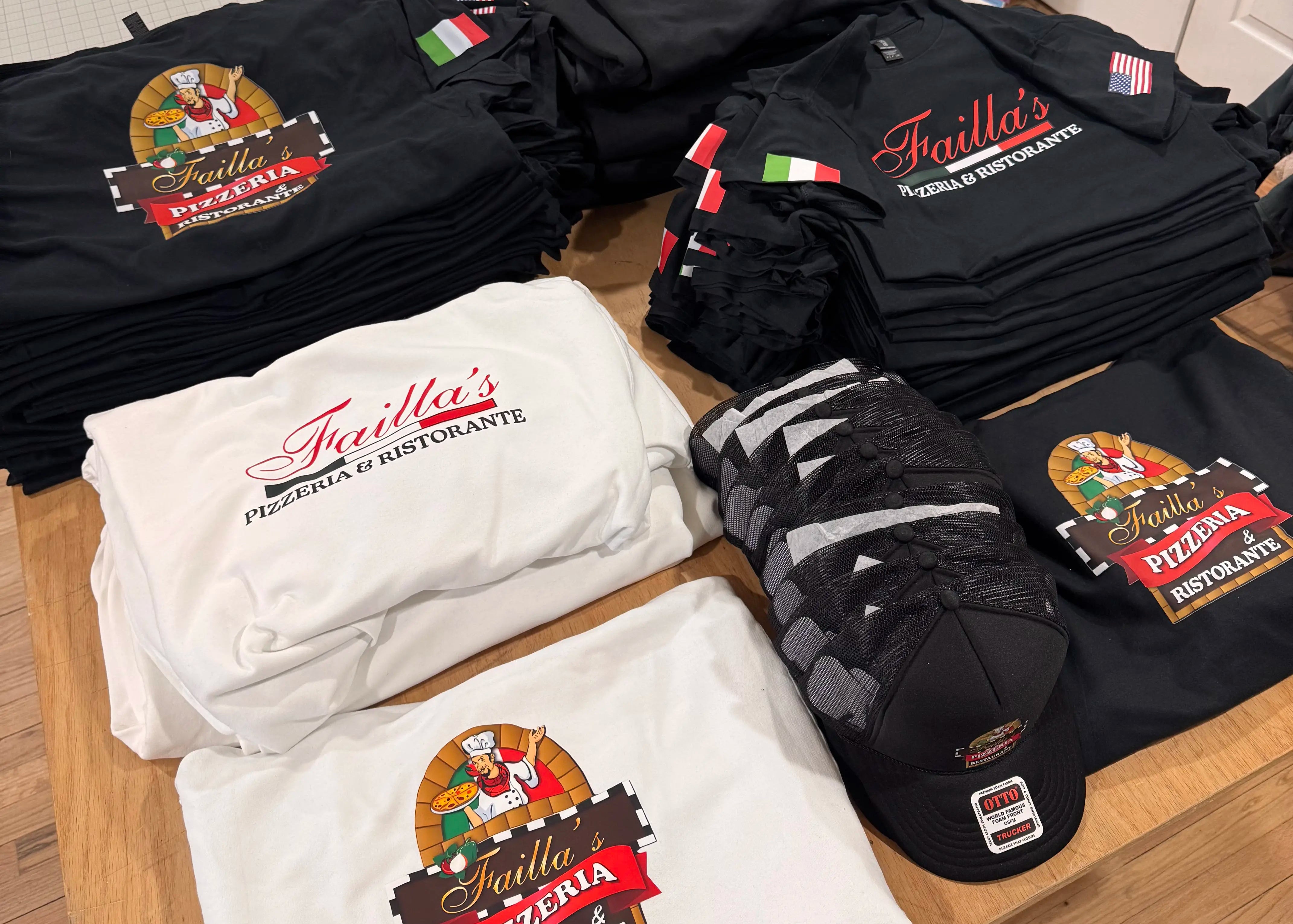 Faillas pizza shirts, hoodies, hats on a wooden table