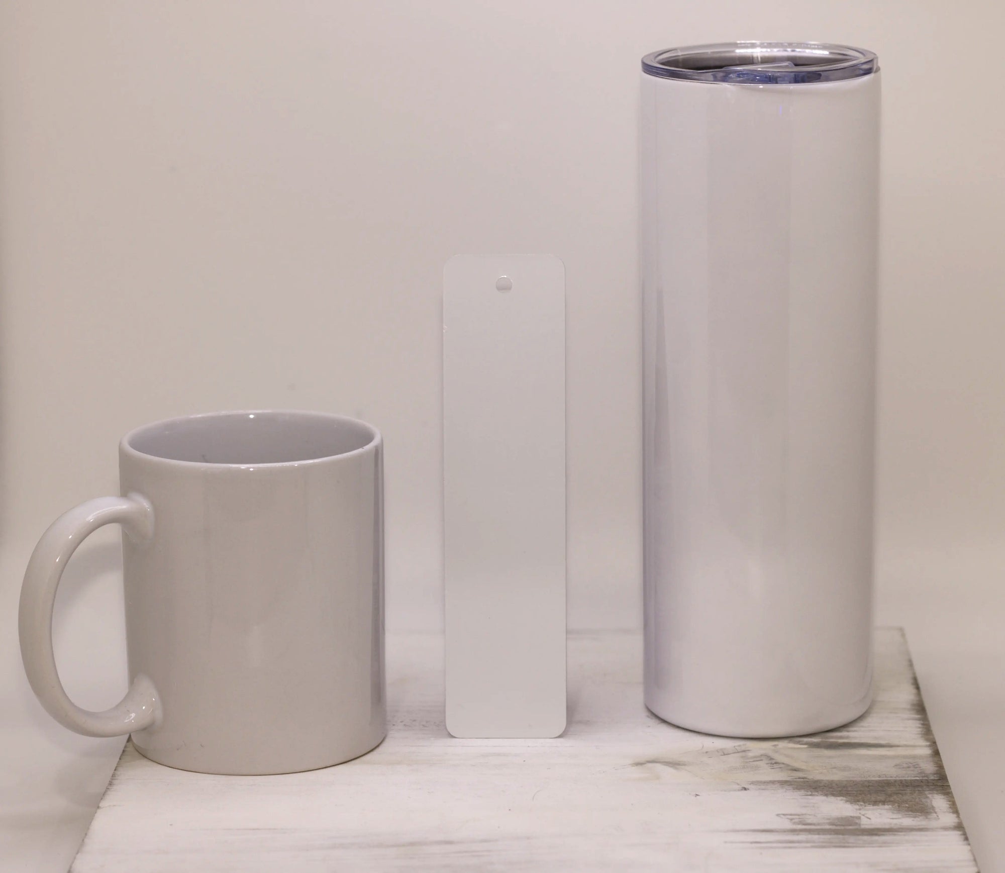 White mug and tumbler on a white surface with a light gray background
