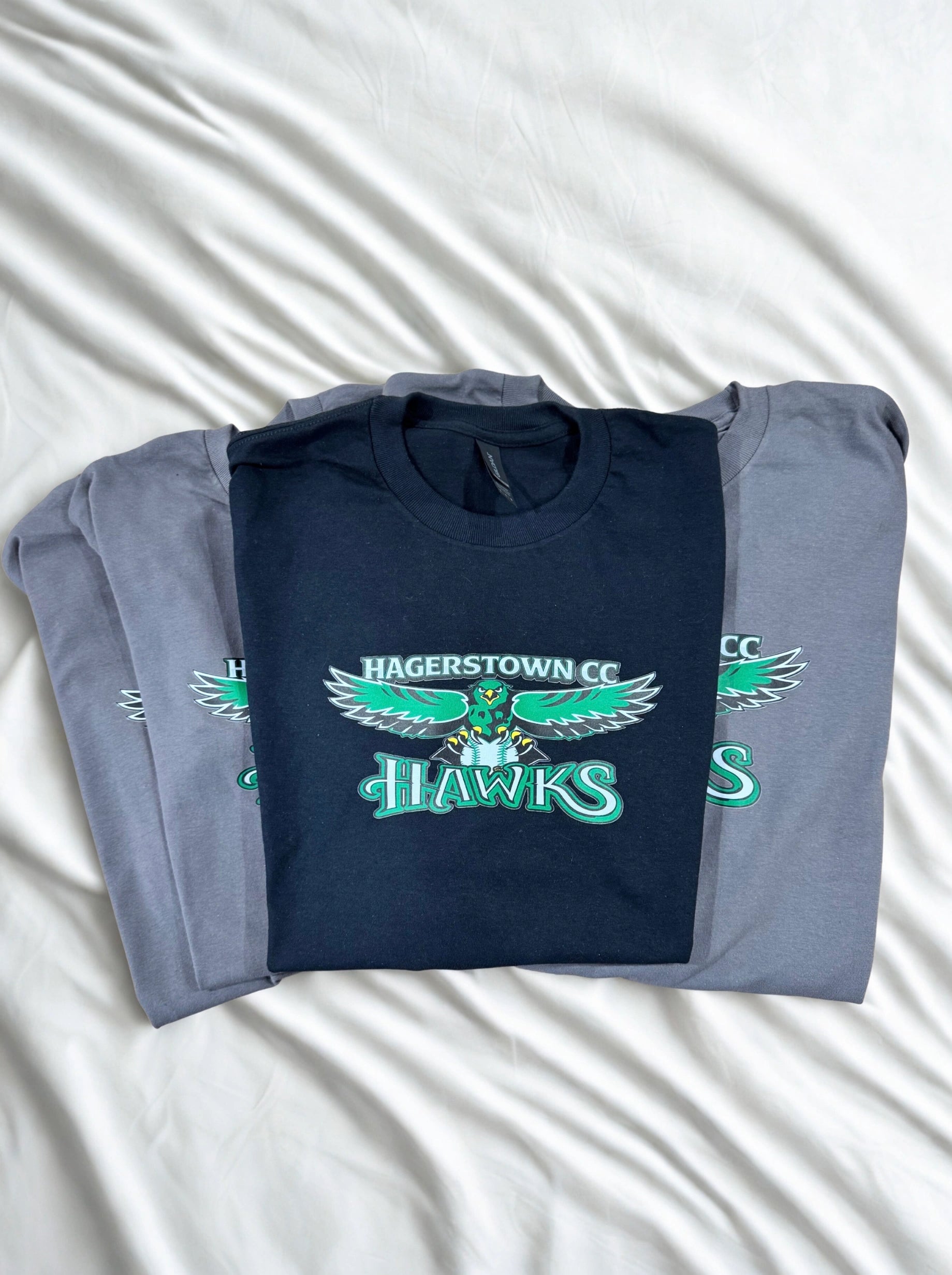 Folded navy blue t-shirt with 'Hagerstown CC Hawks' logo on a white background